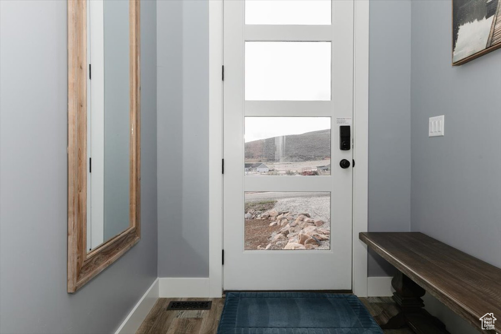 Doorway with visible vents, baseboards, and wood finished floors