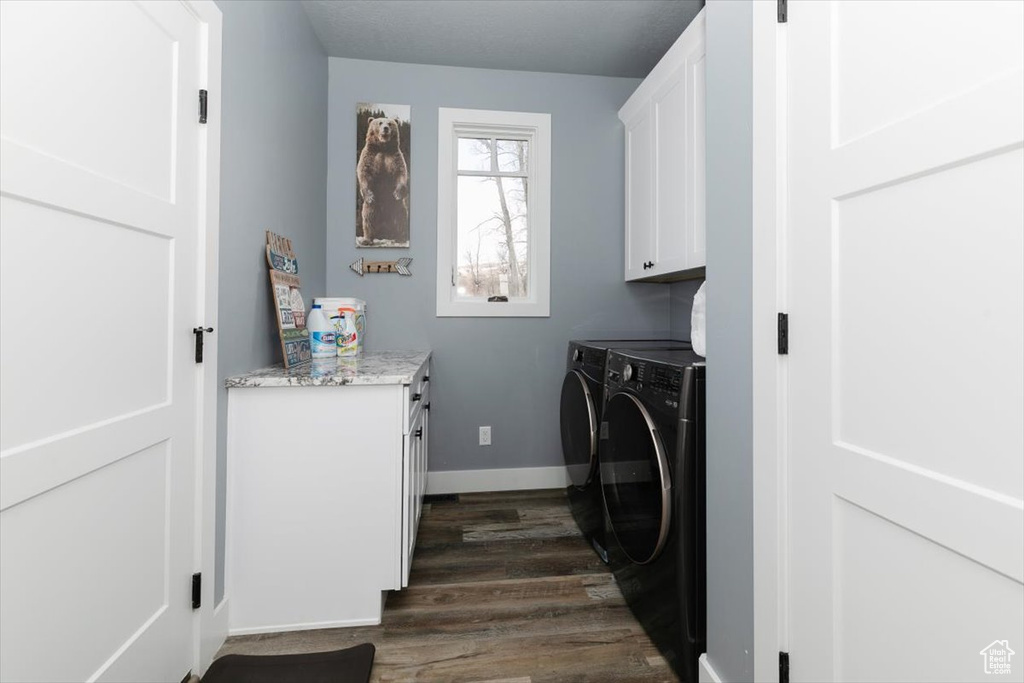 Laundry room with dark wood-style floors, baseboards, washing machine and clothes dryer, and cabinet space