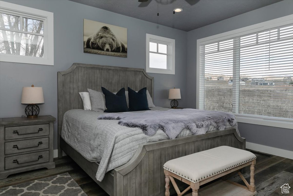 Bedroom with ceiling fan, dark wood-style flooring, and baseboards