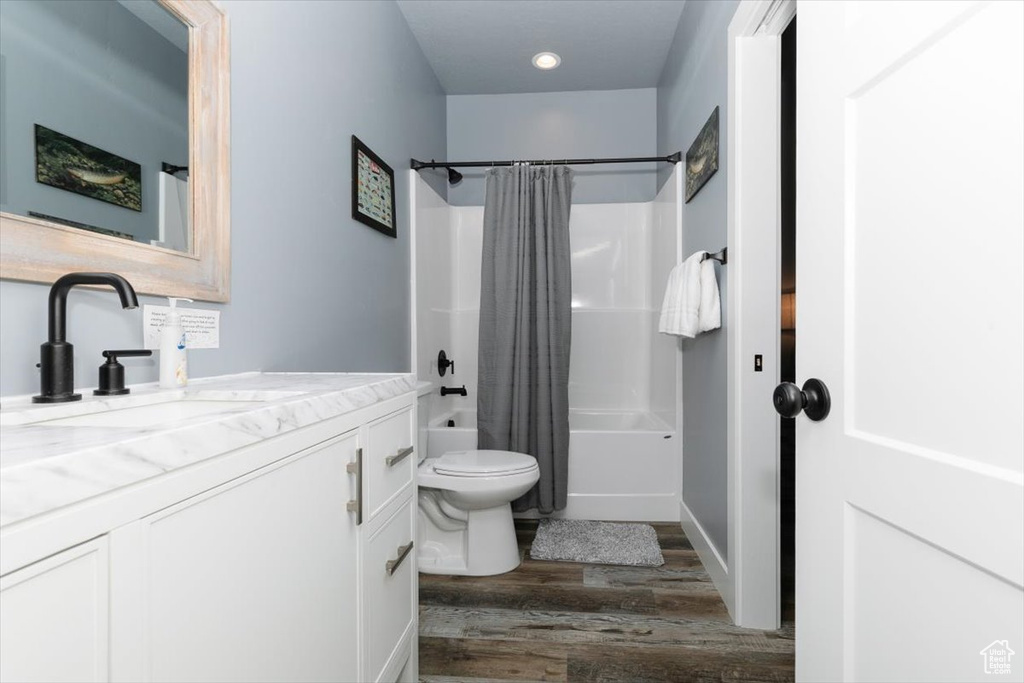 Bathroom with vanity, recessed lighting, toilet, wood finished floors, and shower / tub combo