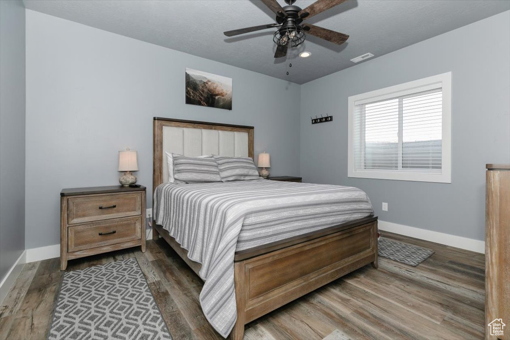 Bedroom with ceiling fan, visible vents, baseboards, and wood finished floors