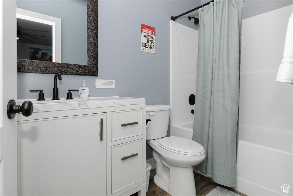 Full bathroom with shower / bath combination with curtain, wood finished floors, vanity, and toilet