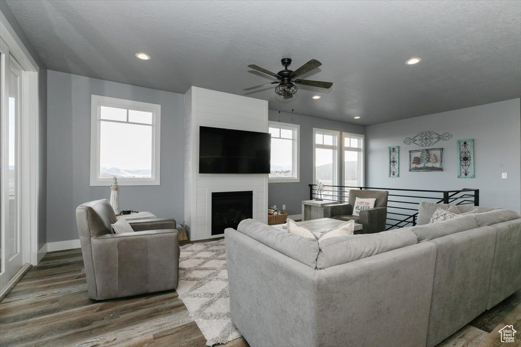 Living area with wood finished floors, ceiling fan, baseboards, and recessed lighting