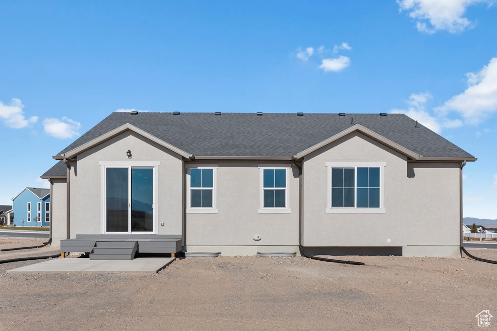 Rear view of property with a shingled roof and stucco siding