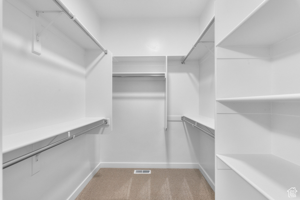Walk in closet with visible vents and light colored carpet