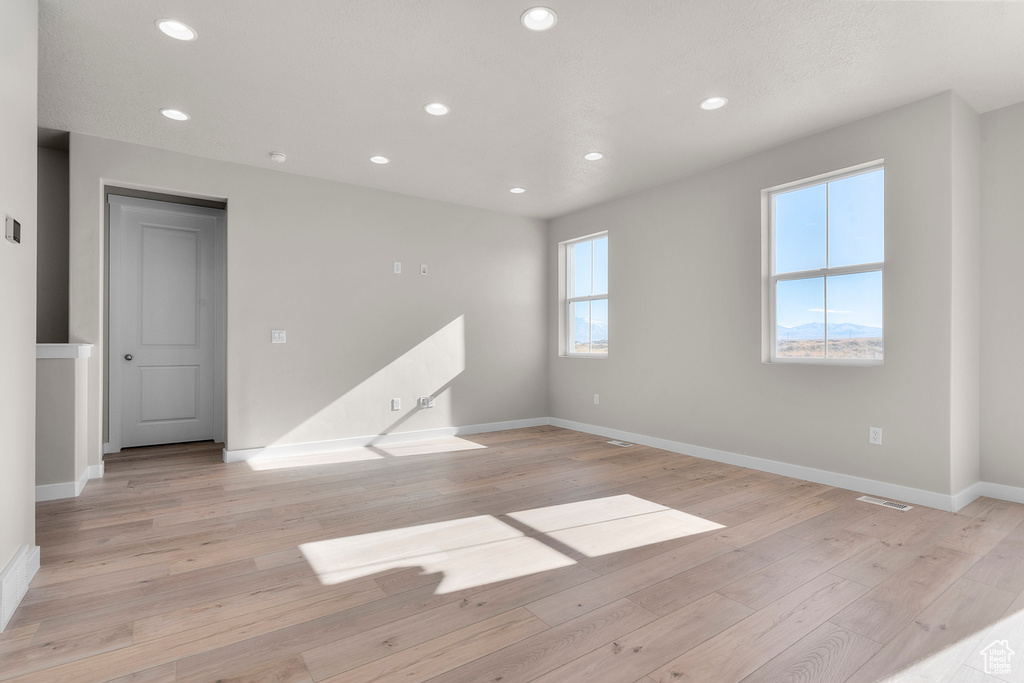 Unfurnished room with recessed lighting, baseboards, light wood-type flooring, and visible vents