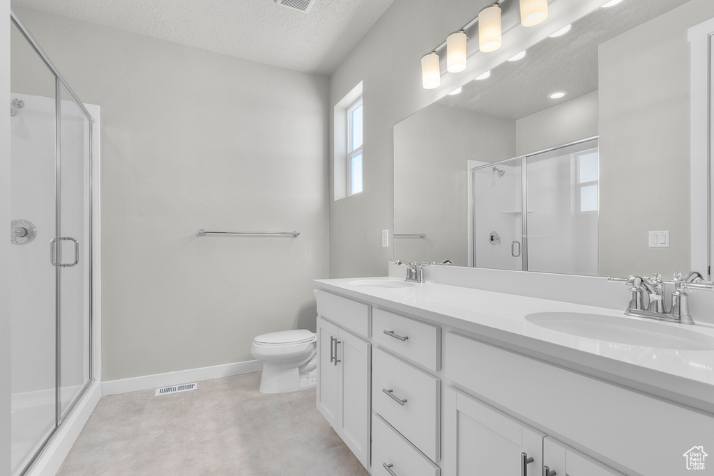 Bathroom featuring visible vents, a sink, a stall shower, and double vanity