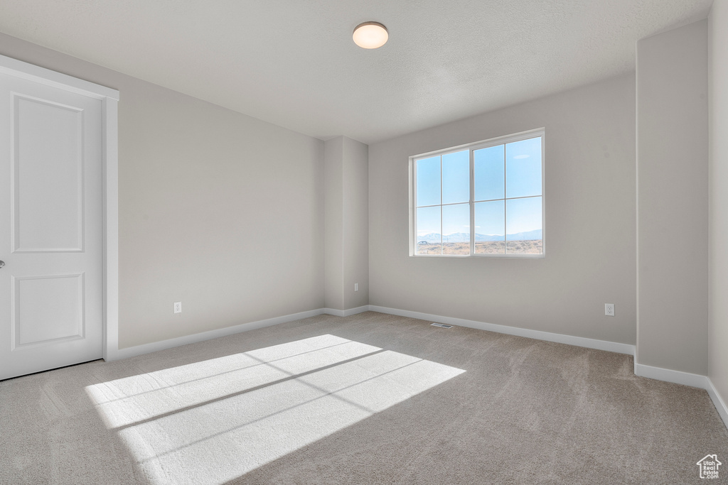 Carpeted spare room featuring baseboards