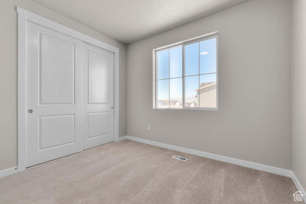 Unfurnished bedroom with baseboards, carpet floors, and visible vents