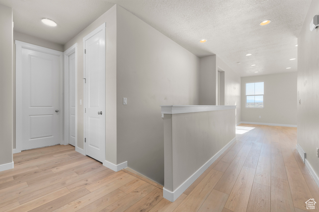 Hall with light wood-style floors, recessed lighting, and baseboards