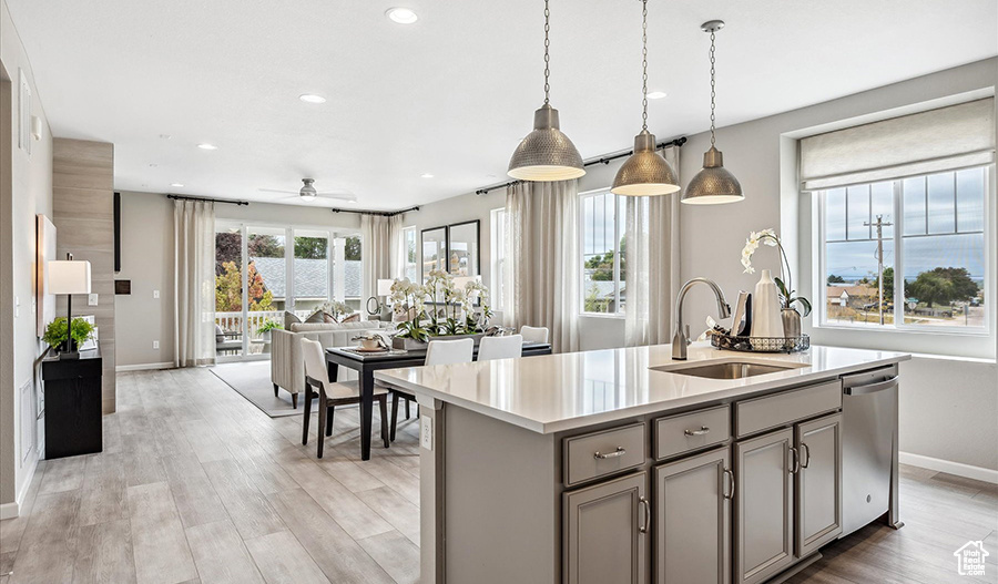 Kitchen with a sink, gray cabinets, open floor plan, baseboards, and stainless steel dishwasher