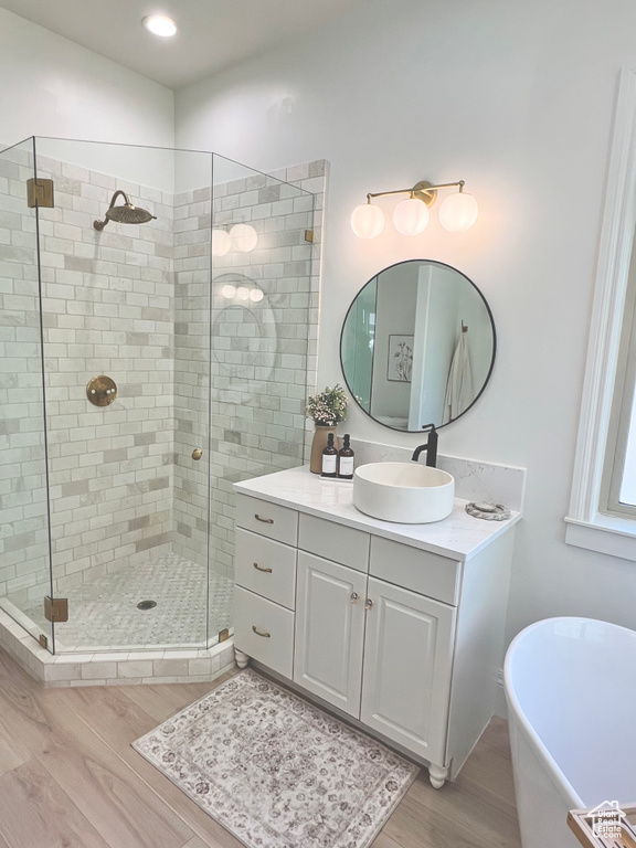 Full bathroom with vanity, a soaking tub, a stall shower, and wood finished floors