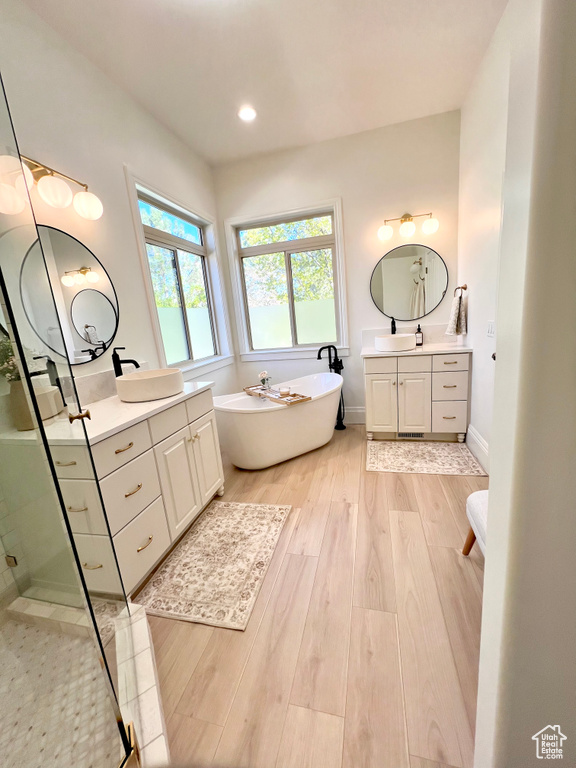 Full bath featuring a sink, wood finished floors, a stall shower, and a soaking tub