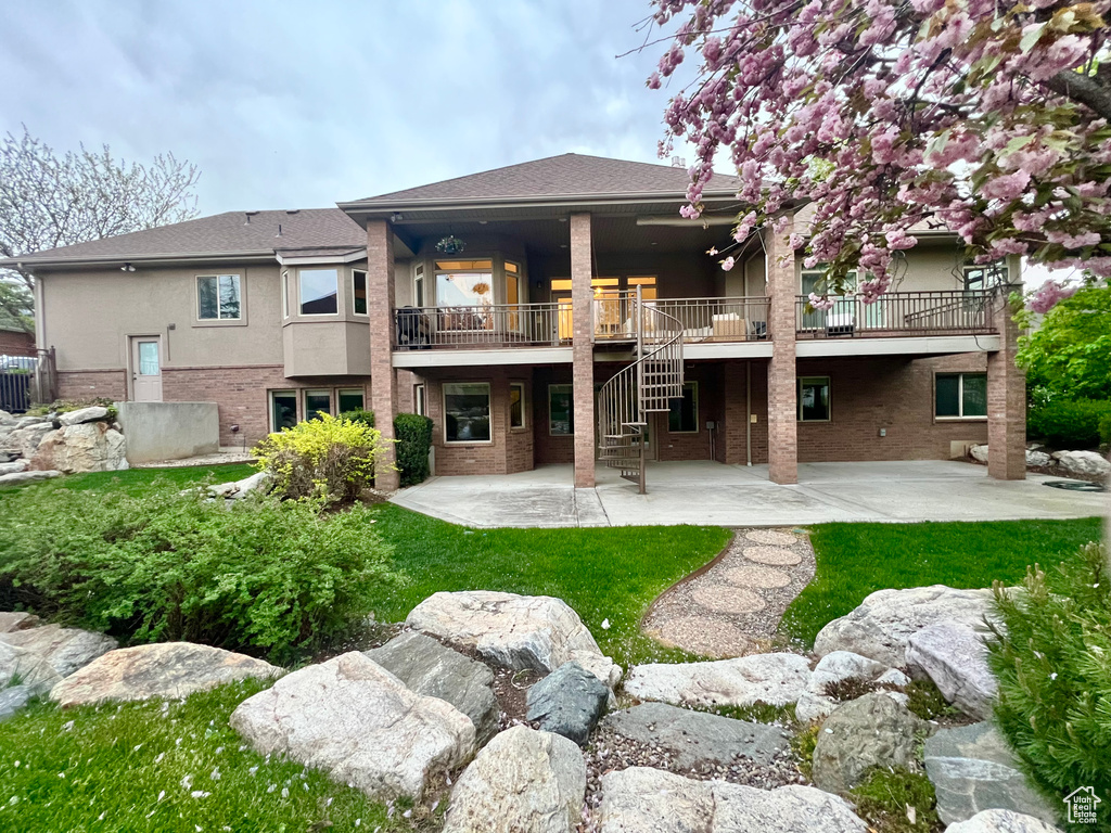 Rear view of property featuring brick siding, stucco siding, a deck, stairway, and a patio area