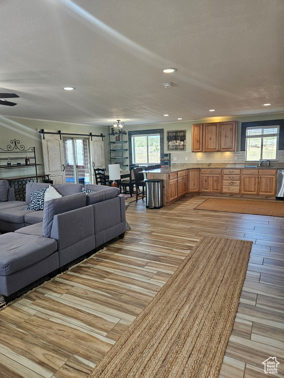 Living room with a barn door, light wood-style flooring, and a wealth of natural light