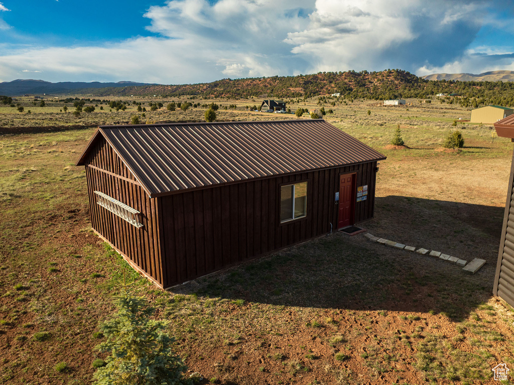 View of outbuilding with a rural view, an outdoor structure, and a mountain view