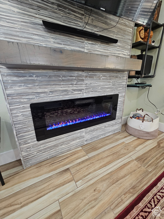 Interior details with baseboards, a glass covered fireplace, and wood finished floors