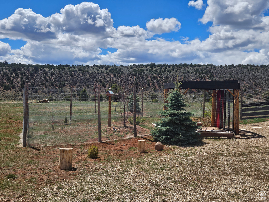 View of yard with a view of trees, fence, and a rural view
