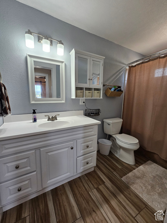 Bathroom with vanity, wood finished floors, toilet, and a shower with curtain