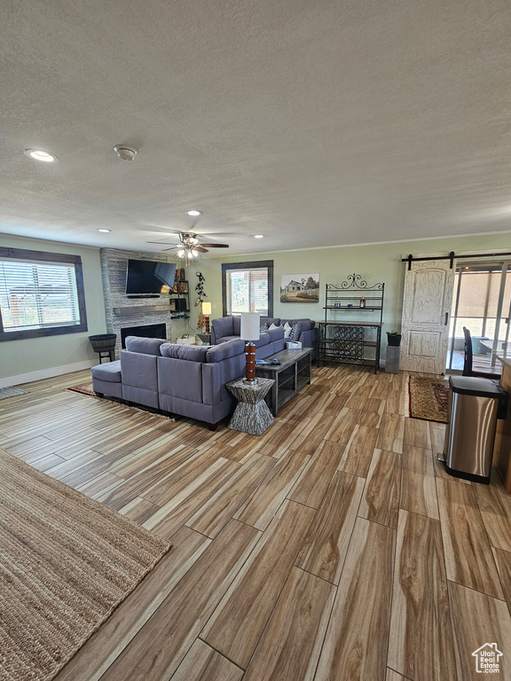Living area with a textured ceiling, a large fireplace, wood finished floors, and a healthy amount of sunlight