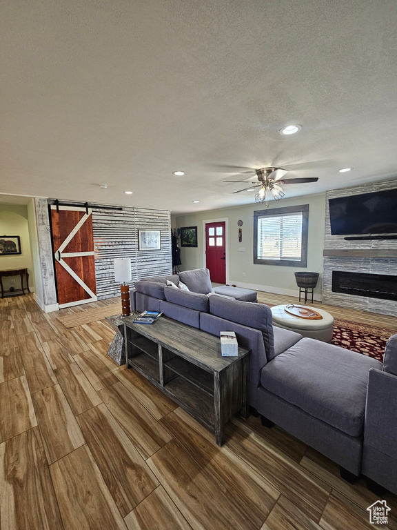 Living area with a textured ceiling, a fireplace, recessed lighting, and a barn door