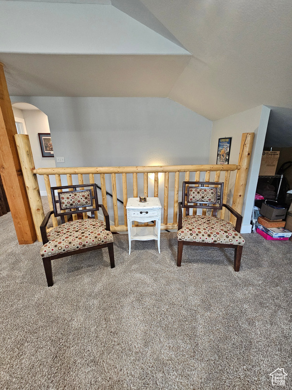 Living area featuring arched walkways, lofted ceiling, and carpet