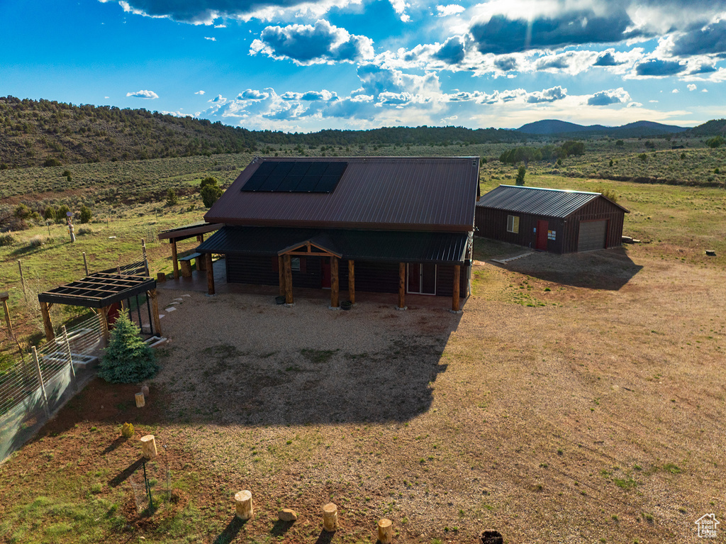 Exterior space featuring a detached garage, an outdoor structure, a mountain view, metal roof, and a rural view