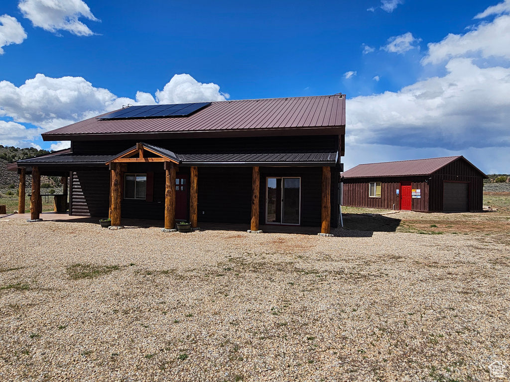 View of front of house with a detached garage, an outdoor structure, solar panels, and metal roof