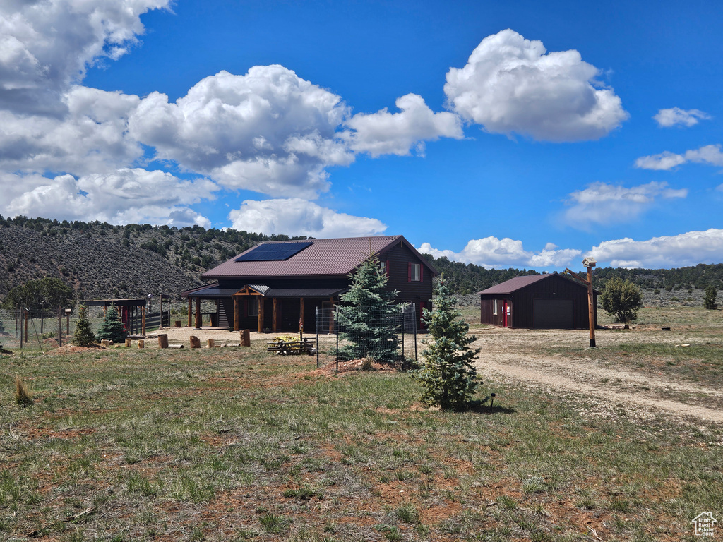 Exterior space with a garage, an outdoor structure, solar panels, and driveway