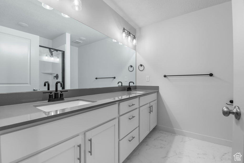 Bathroom with double vanity, baseboards, a sink, and marble finish floor