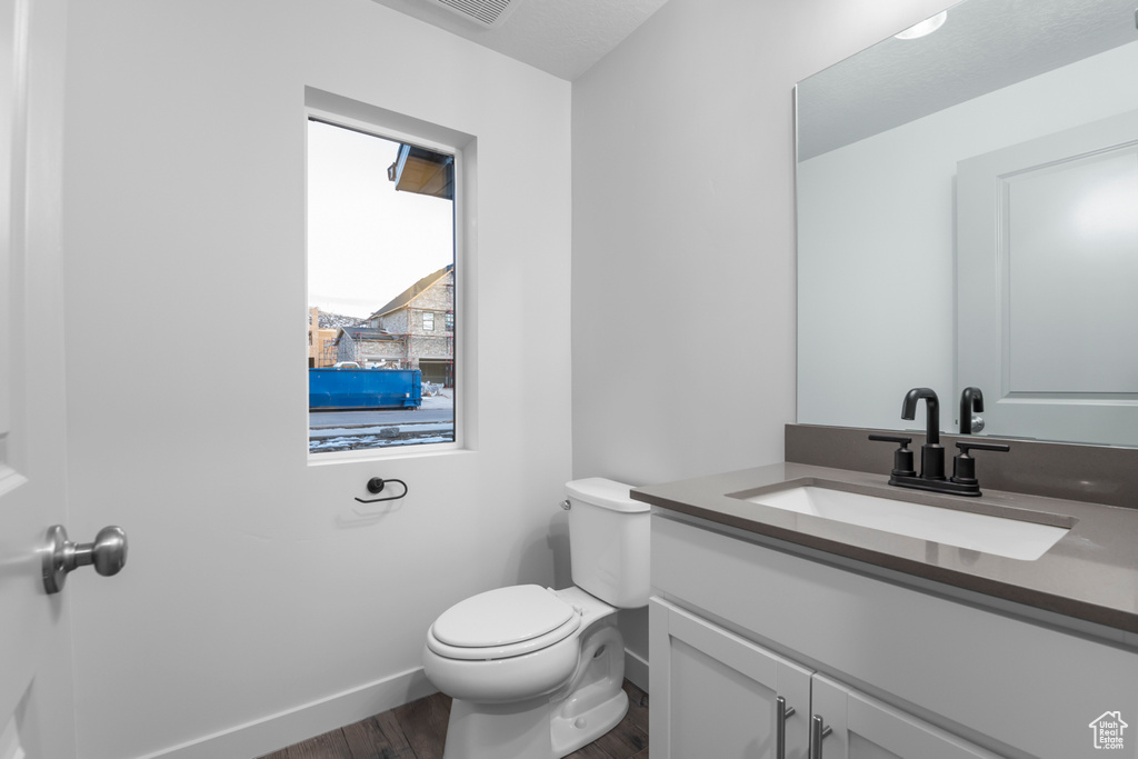 Bathroom with vanity, baseboards, toilet, and wood finished floors