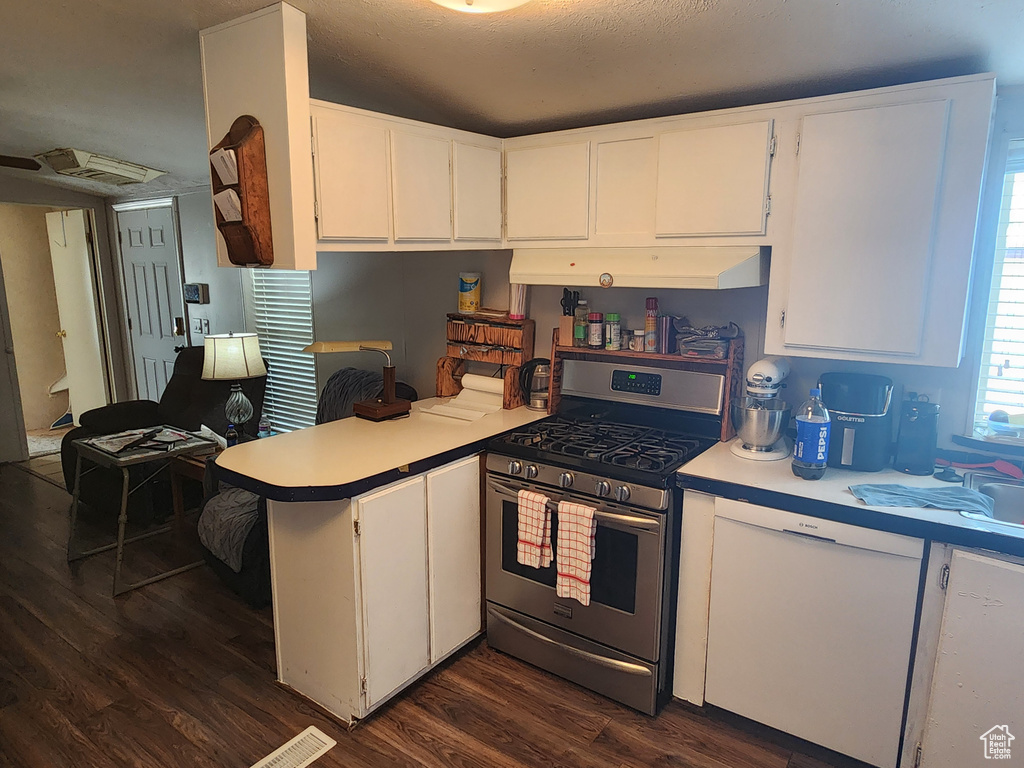 Kitchen featuring dark wood finished floors, light countertops, stainless steel gas range, a peninsula, and under cabinet range hood