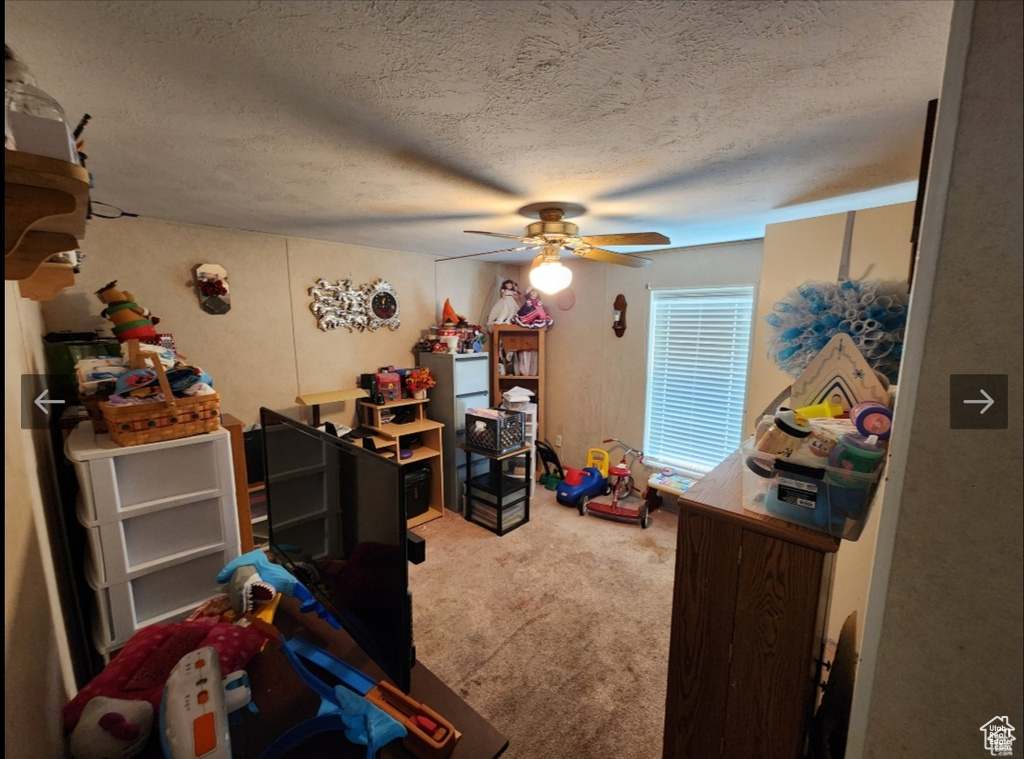 Bedroom with carpet floors, a textured ceiling, and ceiling fan