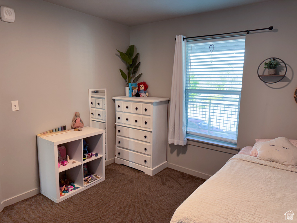Bedroom featuring baseboards, dark carpet, and multiple windows