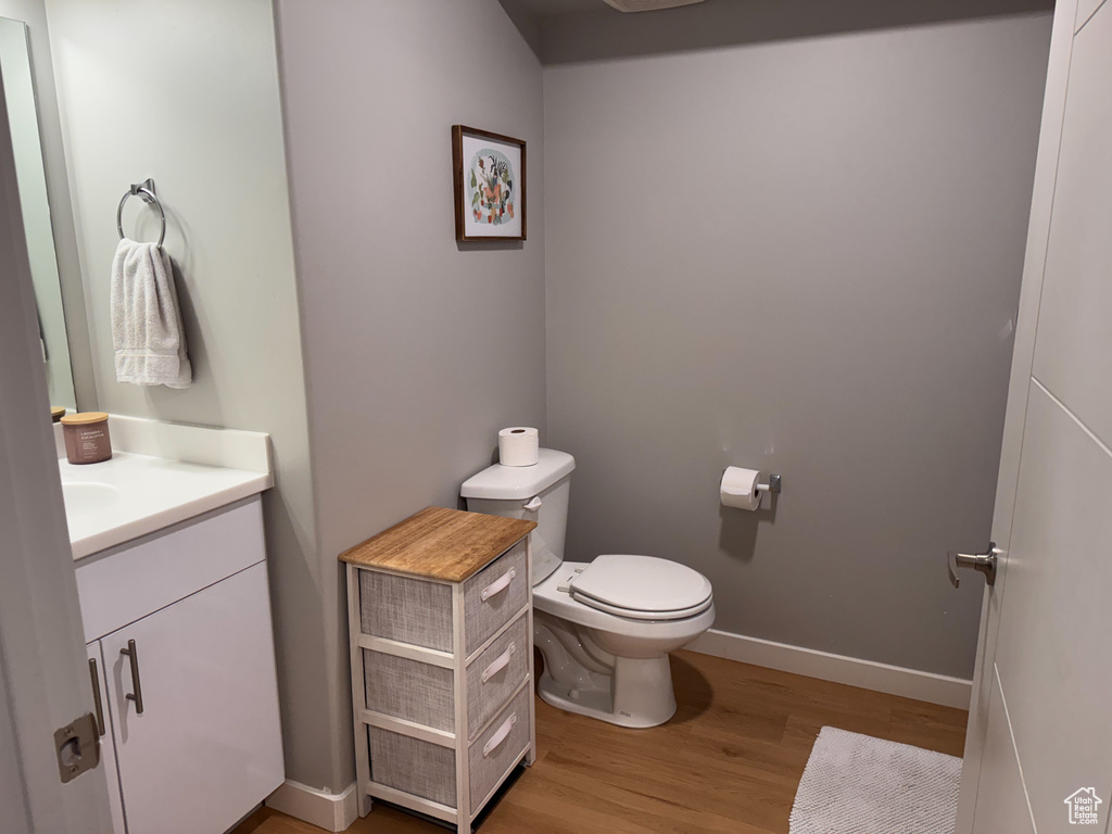 Bathroom featuring toilet, vanity, wood finished floors, and baseboards