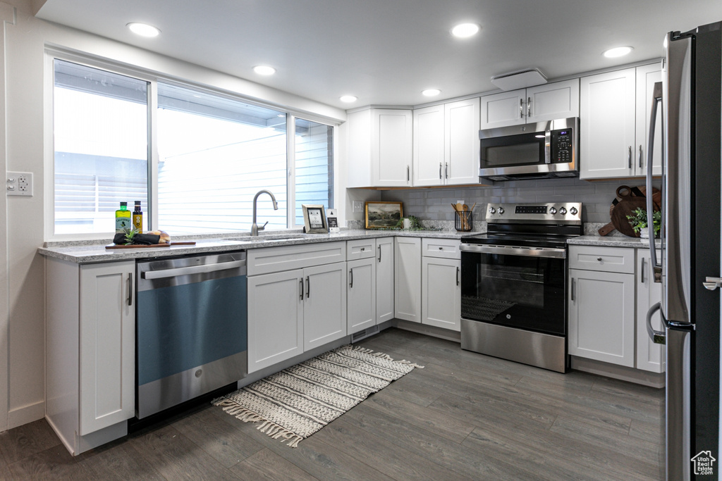 Kitchen with plenty of natural light, a sink, backsplash, and appliances with stainless steel finishes
