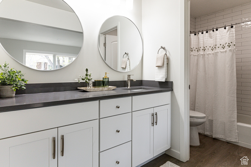 Bathroom with shower / bath combination with curtain, toilet, vanity, and wood finished floors