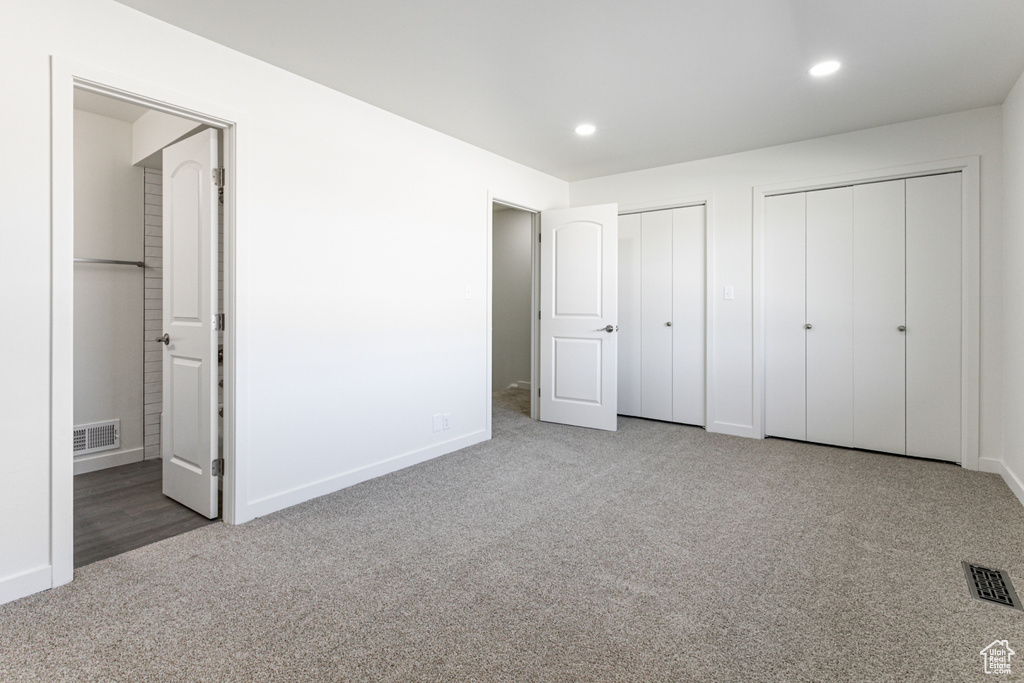 Unfurnished bedroom featuring visible vents, carpet floors, recessed lighting, and two closets