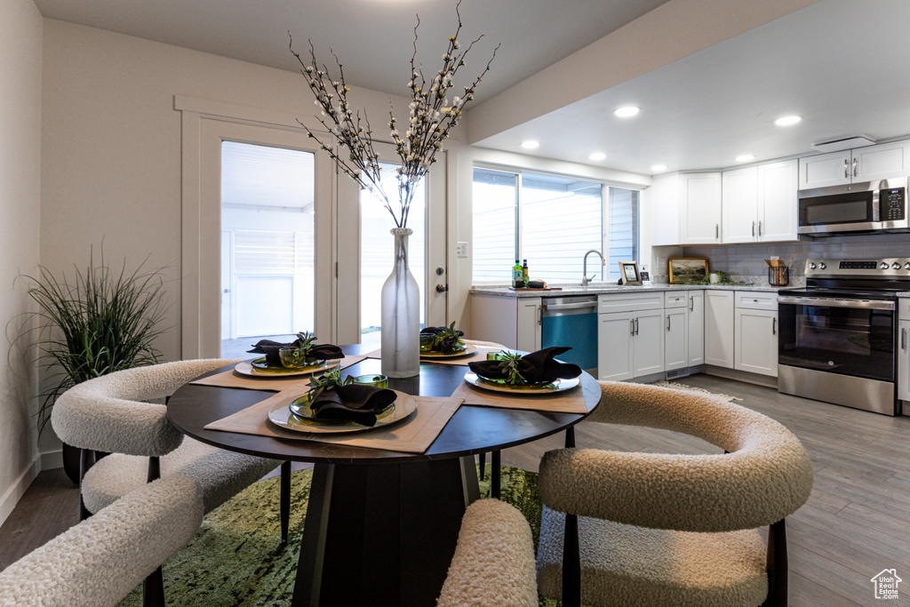 Dining area with recessed lighting and light wood-type flooring
