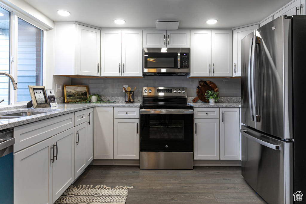 Kitchen with white cabinets, stainless steel appliances, decorative backsplash, and a sink