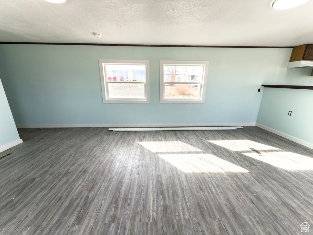 Interior space featuring a textured ceiling, baseboards, and wood finished floors