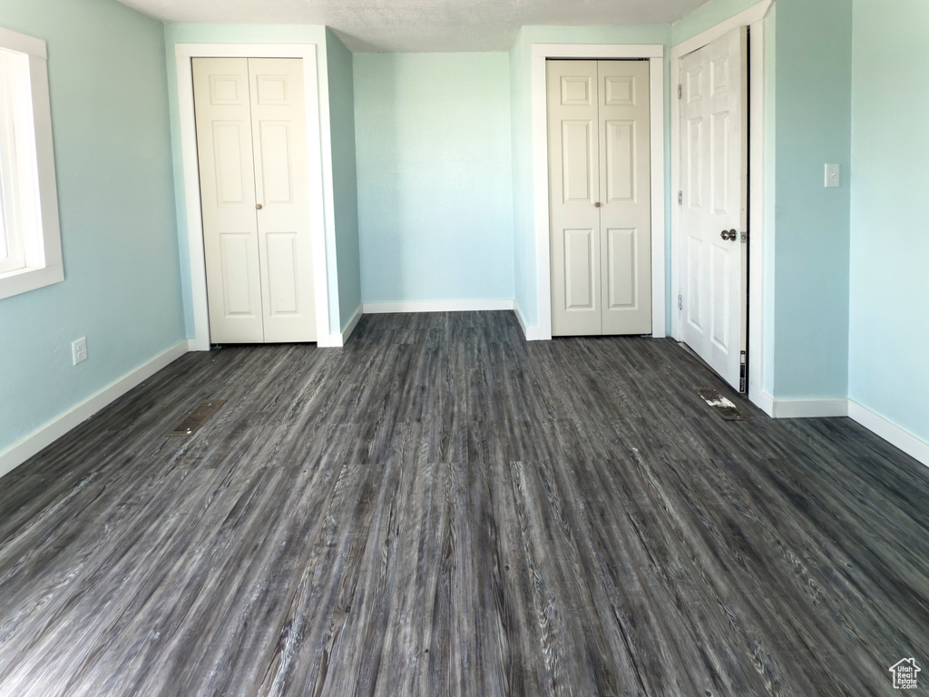 Unfurnished bedroom featuring baseboards and dark wood-style floors