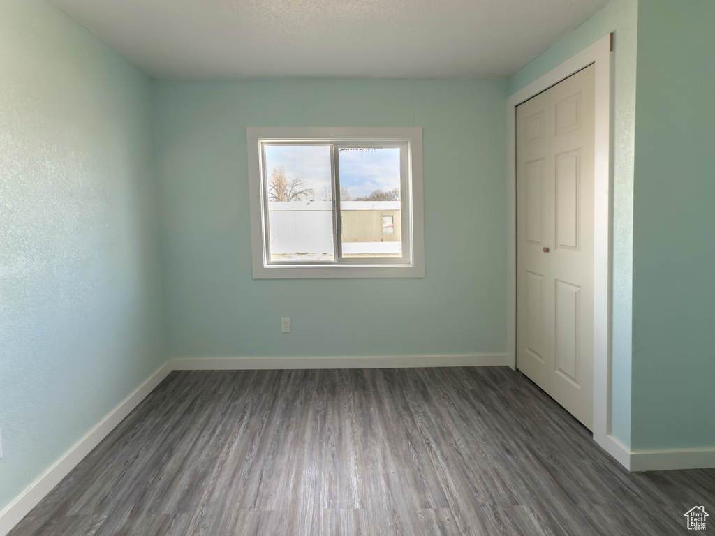 Unfurnished bedroom featuring baseboards and dark wood-type flooring