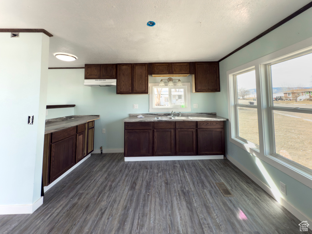 Kitchen with under cabinet range hood, baseboards, and dark wood finished floors