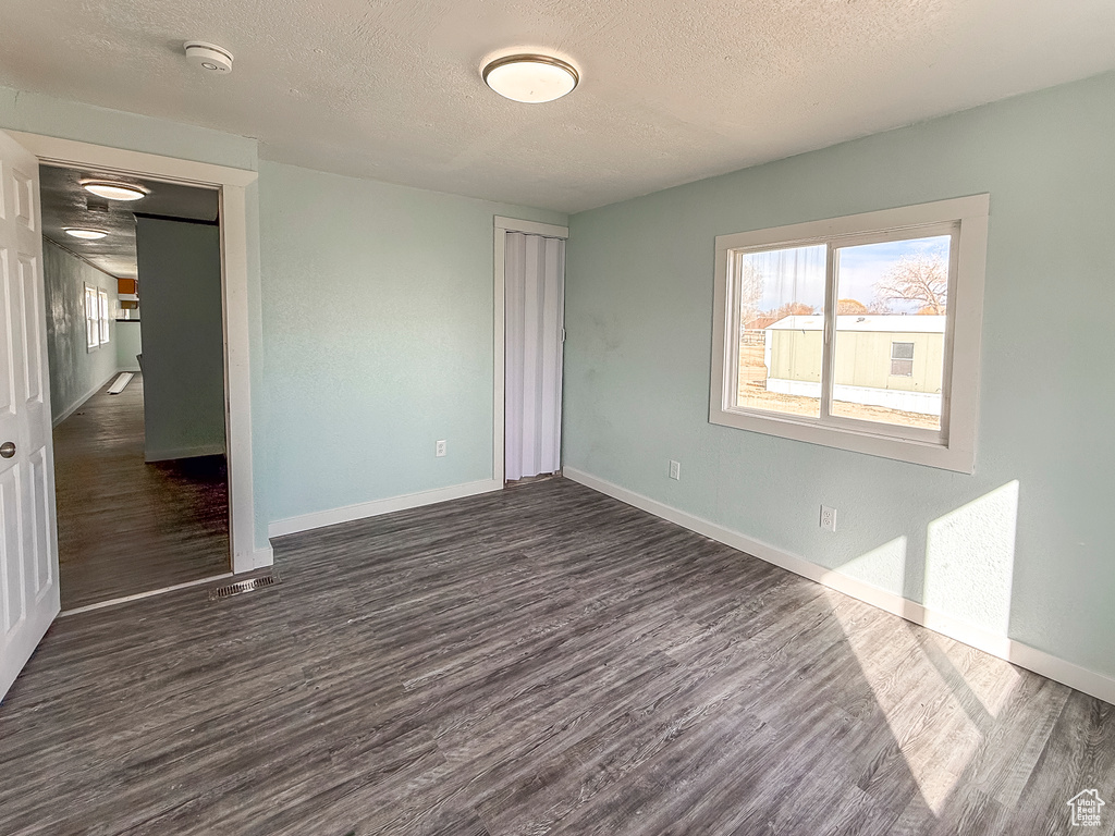 Unfurnished bedroom with baseboards, a closet, dark wood finished floors, and a textured ceiling