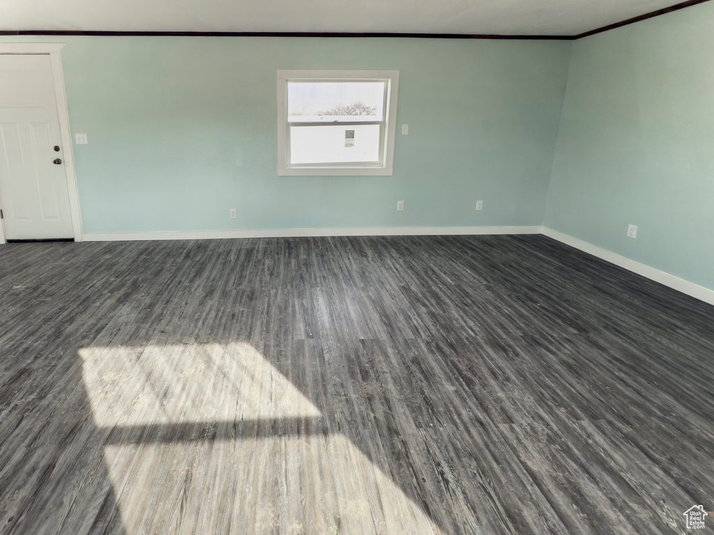 Unfurnished room with baseboards, dark wood-style flooring, and crown molding