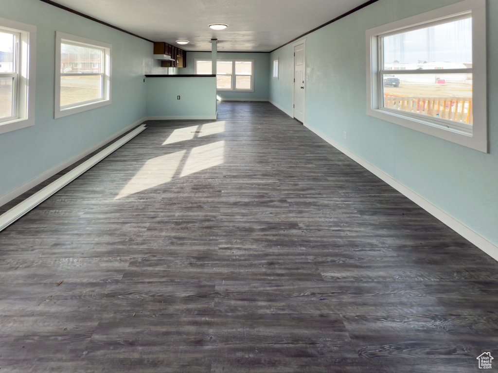 Unfurnished living room featuring baseboards and dark wood-style floors