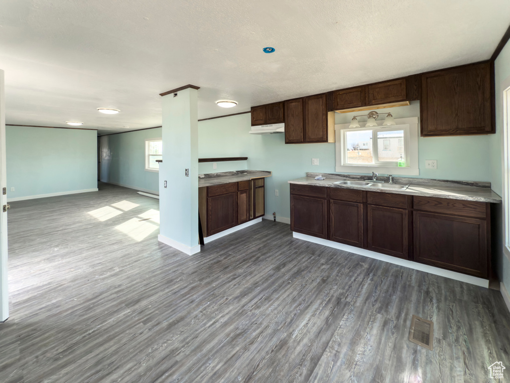 Kitchen featuring open floor plan, visible vents, dark wood-style floors, and a sink
