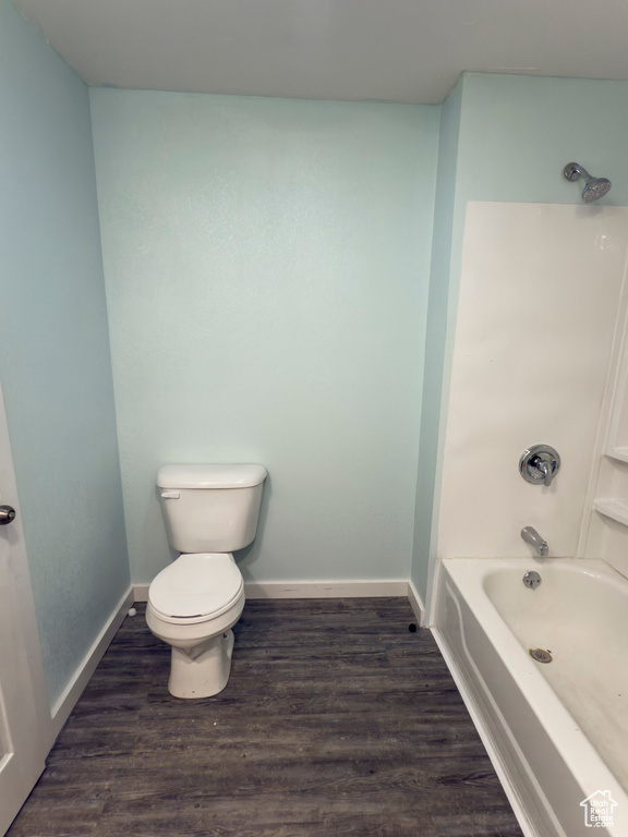 Full bathroom featuring baseboards, wood finished floors, bathing tub / shower combination, and toilet