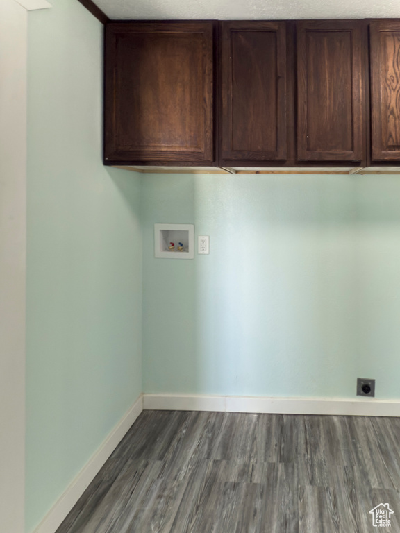 Clothes washing area featuring electric dryer hookup, cabinet space, baseboards, hookup for a washing machine, and dark wood-type flooring